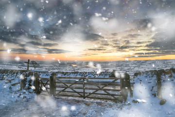 Stunning Winter sunset over snow covered Winter landscape in Peak District in heavy snow storm