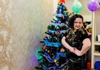 young woman in evening gress near the christmas tree