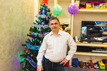 young man in a white shirt near the christmas tree