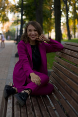 Naklejka na ściany i meble A girl in trendy plum and bright suit walks around the city and has fun. Style.