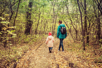 Mother and daughter are walking in the autumn forest