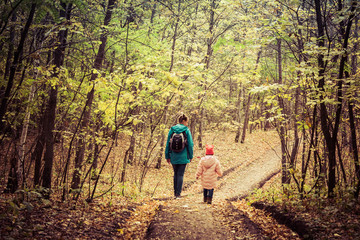 Fototapeta premium Mother and daughter are walking in the autumn forest