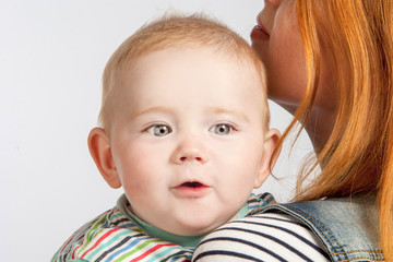 Cute baby in his mother's arms close up.