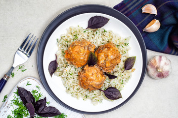 Meatballs and rice in a white and black plates with herbs and basil