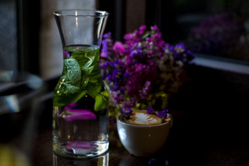 Beautiful glass pitchers with mint, water and fruits. Dishes in the café. Dark background. Cups and glasses.