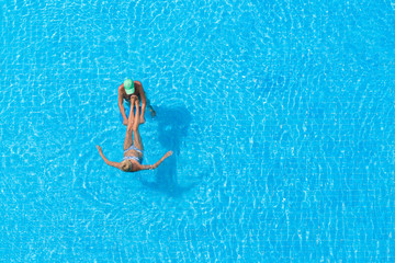 Adult couple relaxing swims in hotel pool.