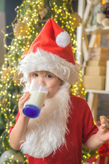 Santa Claus eating cookies and drinking milk on Christmas Eve. Happy santa claus eating a cookie and drinking glass of milk at home. Cookies for Santa Claus child.