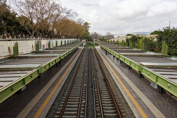 Fototapeta na wymiar Outdoor metro train station in Athens, Greece with two rails and strong perspective view
