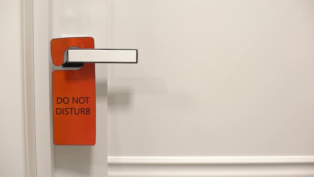 Hand knocks door in spite sign Do not disturb, violating privacy of hotel guest