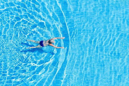 Top view of an adult woman floating in an outdoor pool.