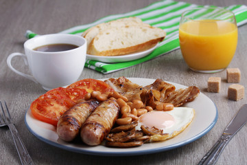 Classic English breakfast served: eggs, bacon, beans, juice and tea	