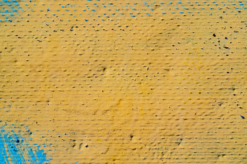 Surface painted yellow with blue paint strokes in the corners. Rough texture with different colors. Bright background for text or design