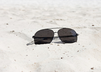 Eyewear placed on the sand at the beach.