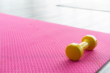 yellow dumbbells on an empty pink rubber floor on wooden floor background,top view with copy space health and exercise concept