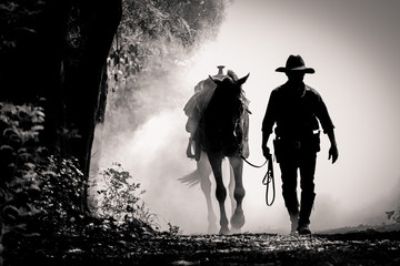 Schwarz-Weiß-Bild Silhouette des Cowboys und des Pferdes bei Sonnenaufgang am Morgen