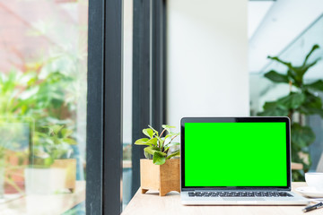 Mockup of laptop computer with empty screen with coffee cup on table of the coffee shop background,Green screen