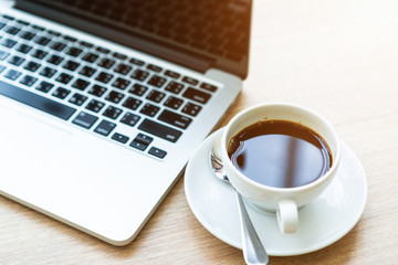 Close-up of Business laptop computer and coffee cup on wooden table of In the coffee shop background