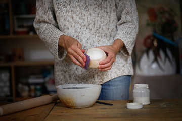Caucasian craftswoman enamels clay cup in workshop