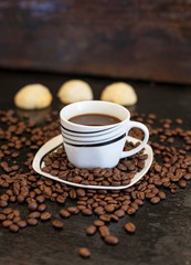 black coffee and spilled coffee beans decorated on an old wooden table.