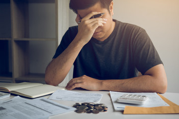 Asian men are stressed about financial problems, with invoices and calculators placed on the table...