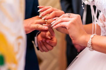 Obraz na płótnie Canvas Bride wearing gold wedding ring on the grooms finger