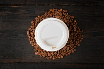  Paper cup of coffee and coffee beans on dark wooden table. Good quality coffee