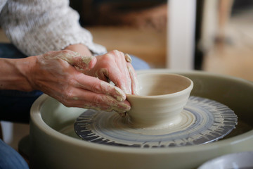 woman makes cup of clay on potter’s wheel