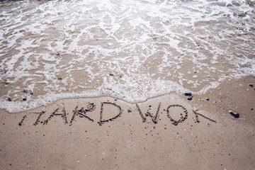 Let's holiday and go to the sea concept. Hard work word on sand wash by wave ocean beach.