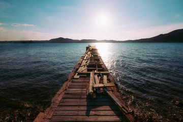 Wooden bridge on the beach to the sea in afternoon summer sky.