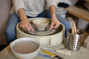 Fototapeta na wymiar woman removes clay cup using thread potter's wheel