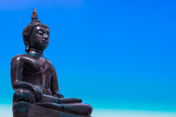 Statue of Buddha sitting in meditation with blue space