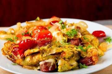 Fresh omelette with onion, pork sausages, tomatoes and cheese