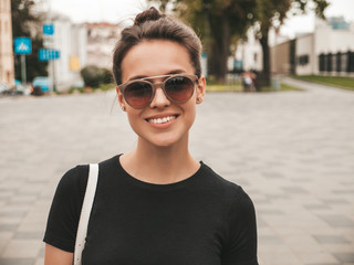 Portrait of beautiful smiling hipster model dressed in summer clothes. Trendy girl posing in the street background in sunglasses. Funny and positive woman having fun