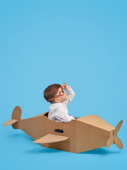 Joyful boy playing with cardboard airplane and exploring sky