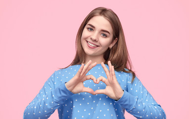 Teenager in pajama showing heart gesture