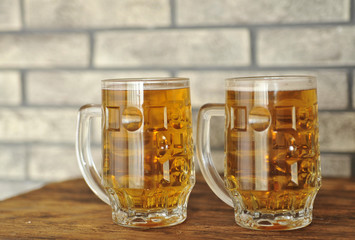 Two glasses of light beer on wooden table. 