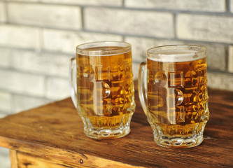 Two glasses of light beer on wooden table. 