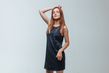 Girl in a dark dress posing on a gray background