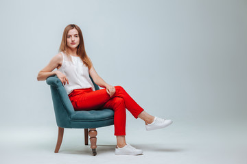 Girl in red pants sitting in a chair on a light gray background
