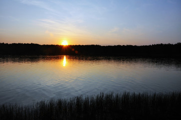 Sunset over the lake. The sky is in red rays.