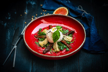 Burata cheese with dried tomatoes, artichokes, arugula and Basil on a red plate. A dish of Italian cuisine is an appetizer.