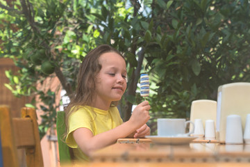  girl eating ice cream at a table on the street