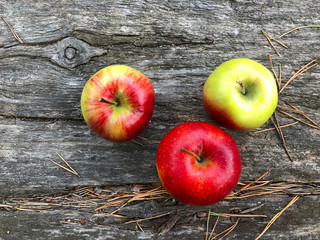 Three fresh apples on a wooden table. Red ripe apples against wooden background, healthy eating concept.