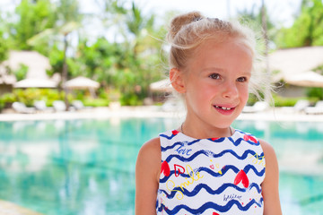 Beautiful child girl near swimming pool. Tropical outdoor background. Copy space.