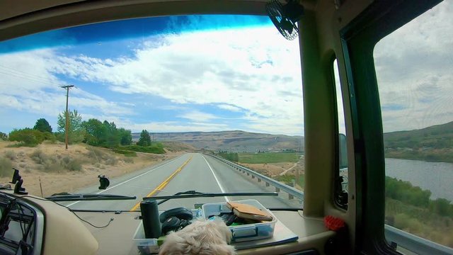 POV of the passenger in a Recreational Vehicle RV while driving through the Scablands of east central Washington State; with the Columbia River to the right and a labradoodle dog in the foreground