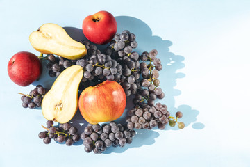 harvested ripe, fresh grapes, pears and apples on a blue background