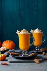 Pumpkin latte with spices. Boozy cocktail with whipped cream on slate board. Grey and blue background. Copy space.