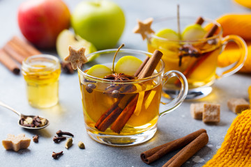 Apple mulled cider with spices in glass cup. Grey stone background. Close up.