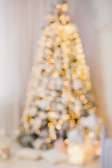 Blurry beautiful Christmas tree standing in livingroom. Vertical color photography.