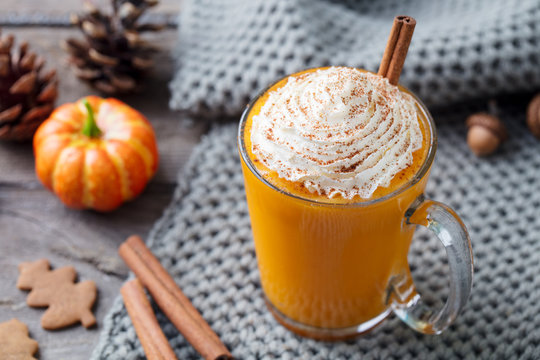 Pumpkin latte with spices. Boozy cocktail with whipped cream. Wooden background. Close up.